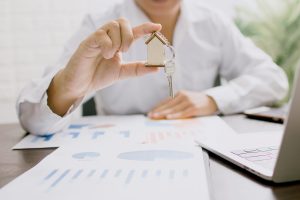 Homme tenant entre ses doigts un porte-clé en forme de maquette de maison avec une clé accrochée dessus fiscalité LMNP LMP