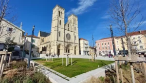 Place centrale de Bourgoin-Jallieu avec l’église Saint-Jean-Baptiste et les bâtiments typiques de la ville sous un ciel bleu