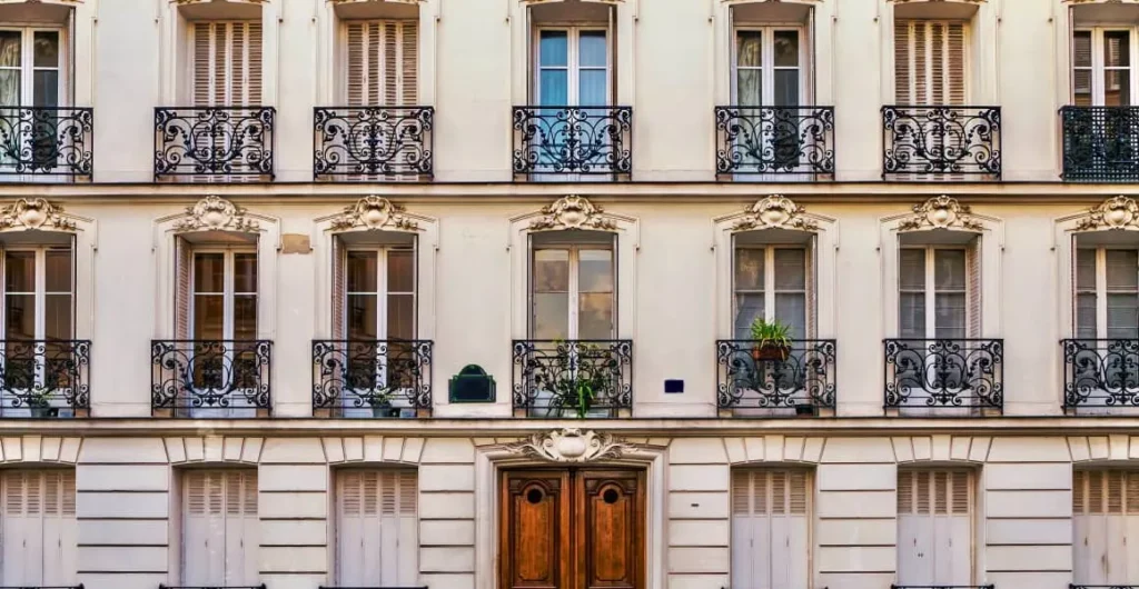 Façade d’un immeuble haussmannien typique à Paris avec des fenêtres à balcons, illustrant les logements concernés par la loi Le Meur sur la location meublée touristique.