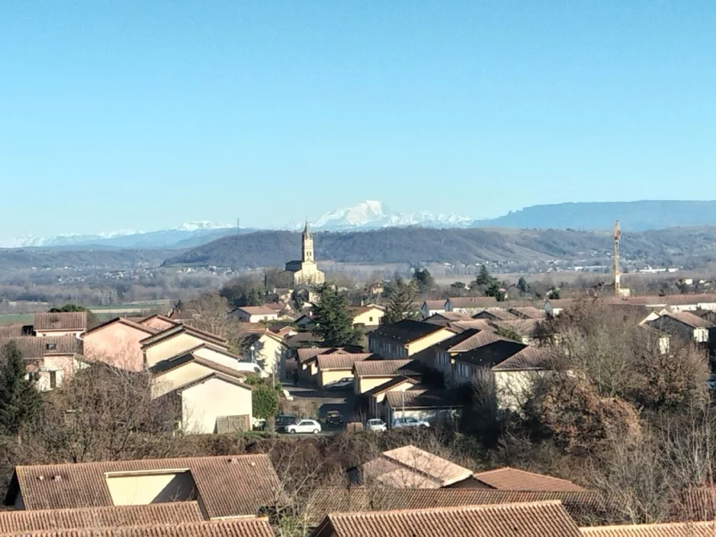 Vue panoramique de l’Isle-d’Abeau avec son église et les Alpes en arrière-plan – expert-comptable OPALE proche de Bourgoin-Jallieu en Isère.