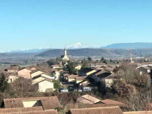 Vue panoramique de l’Isle-d’Abeau avec son église et les Alpes en arrière-plan – expert-comptable OPALE proche de Bourgoin-Jallieu en Isère.